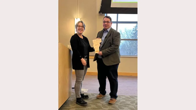 A Vermont-shaped plaque is held up between Dr. Lavoie and Dr. Cryan, posing for a photo