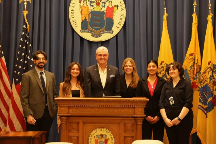 New Jersey students pose at a statehouse podium with Governor Phil Murphy
