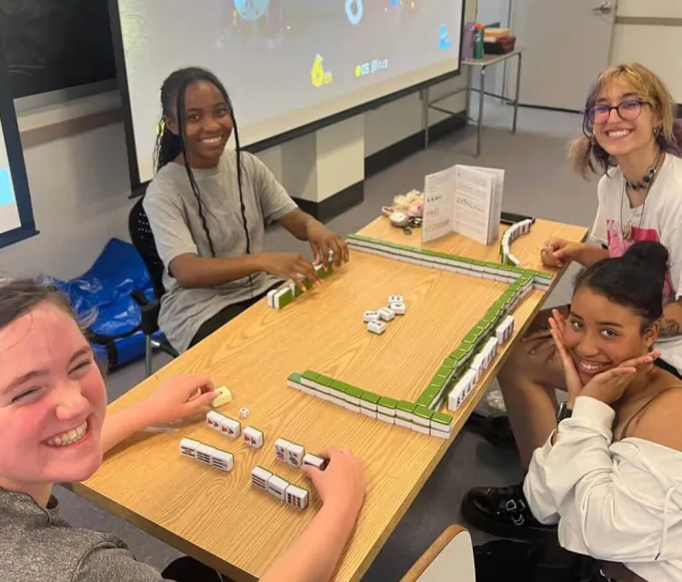 Four students playing mahjong big cube board game