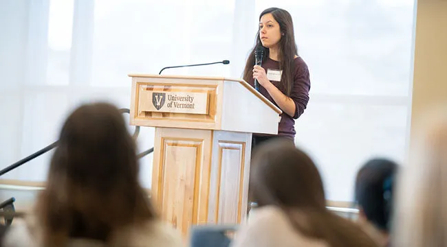 a young Phd students answers questions at the lectern of a conference