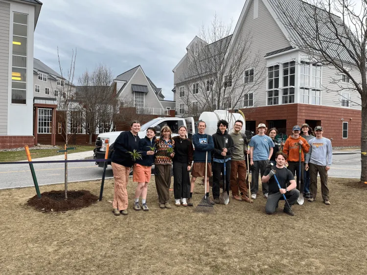 Group of college students with tools next to newly planted maple tree