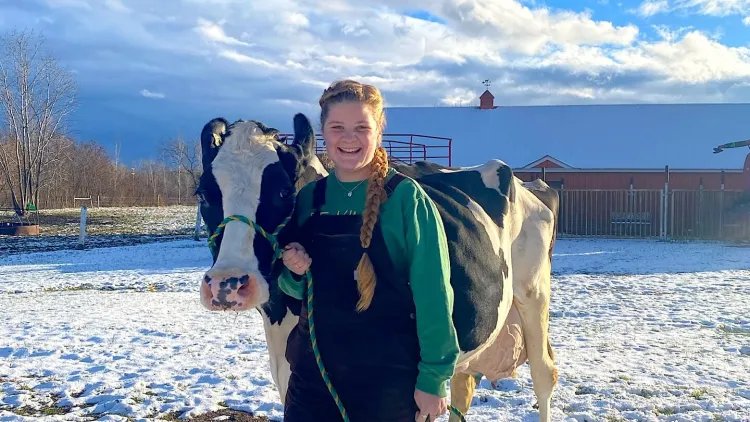 Annie Boudreau with a cow in the pasture at the UVM Dairy Barn.