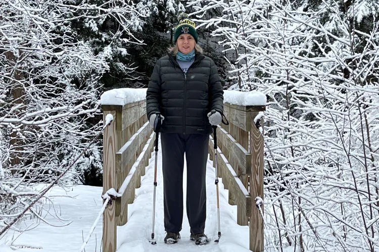 Corinne Thompson hikes across a snow covered bridge