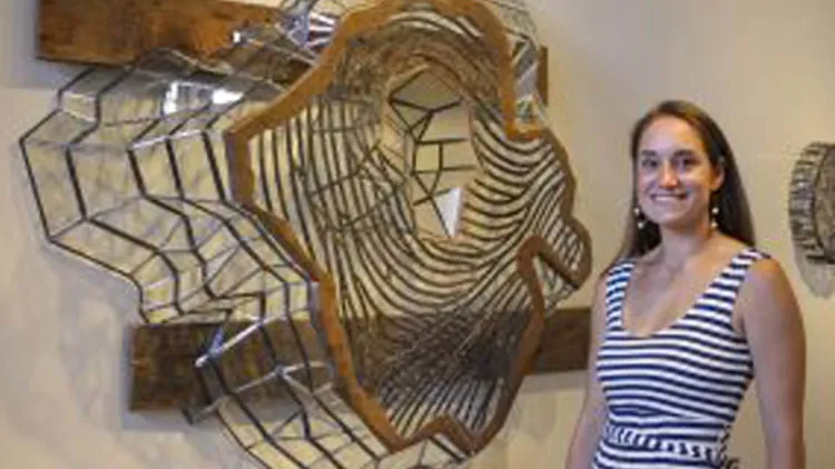 A person stands beside a large metal sculpture