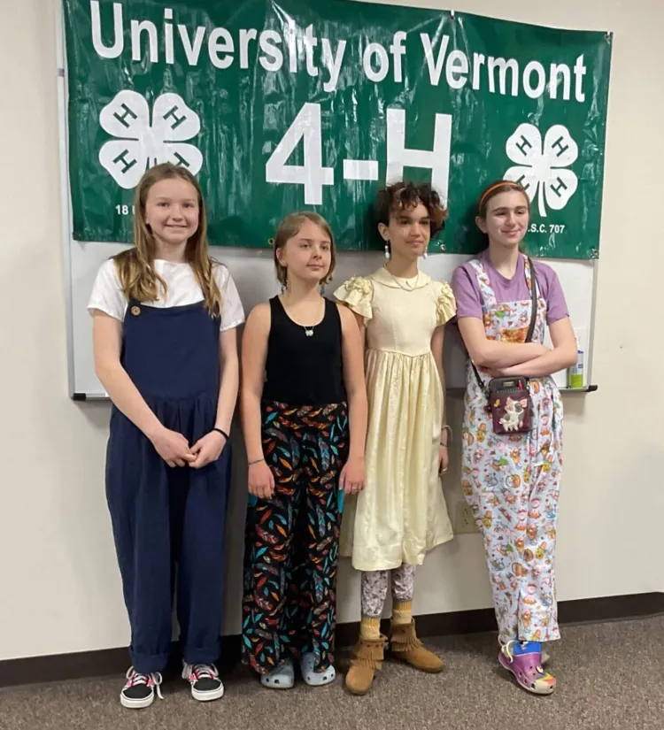 4 kids in front of a 4-H banner