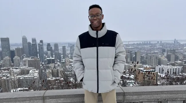 A student standing in front of city skyline