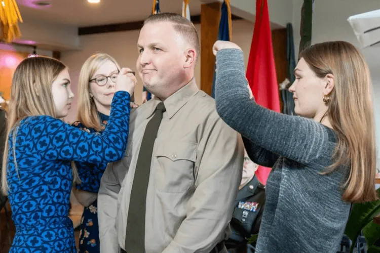 a military man surrounded by his wife and 2 daughters