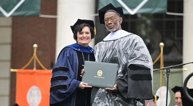 man receiving diploma from woman in regalia
