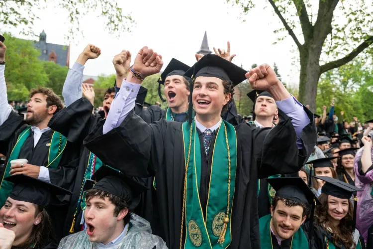 A group of Rubenstein School students standing and cheering at the UVM Commencement ceremony