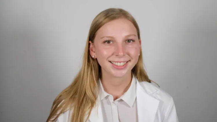 a woman in a white coat smiling