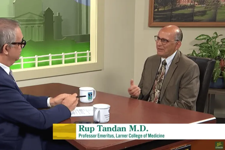 two men talking at a table in a TV studio
