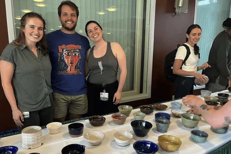 students standing near a table covered with pottery bowls