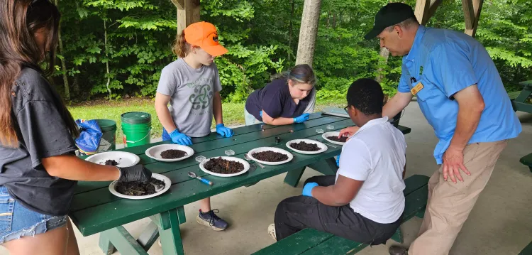 campers examining soil samples at a picnic table
