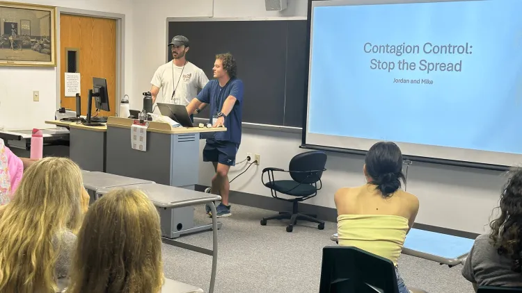 2 Larner medical students instructing a group of students in a classroom