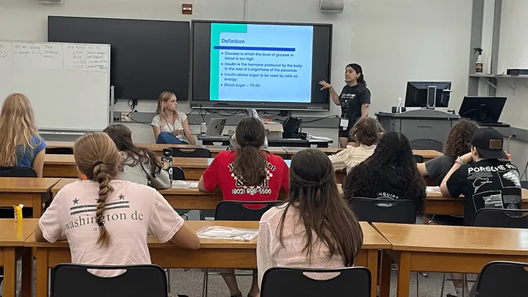 2 Larner medical students instructing a group of high school students in a classroom