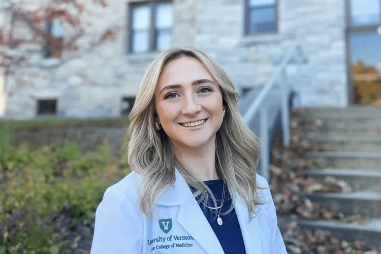 a woman in a white coat in front of a stone building