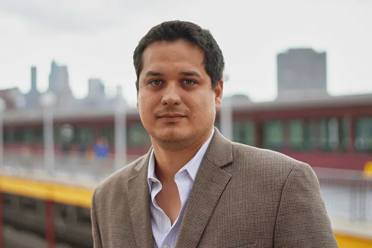 headshot of Dave Punihaole, Ph.D., with a city skyline in the background