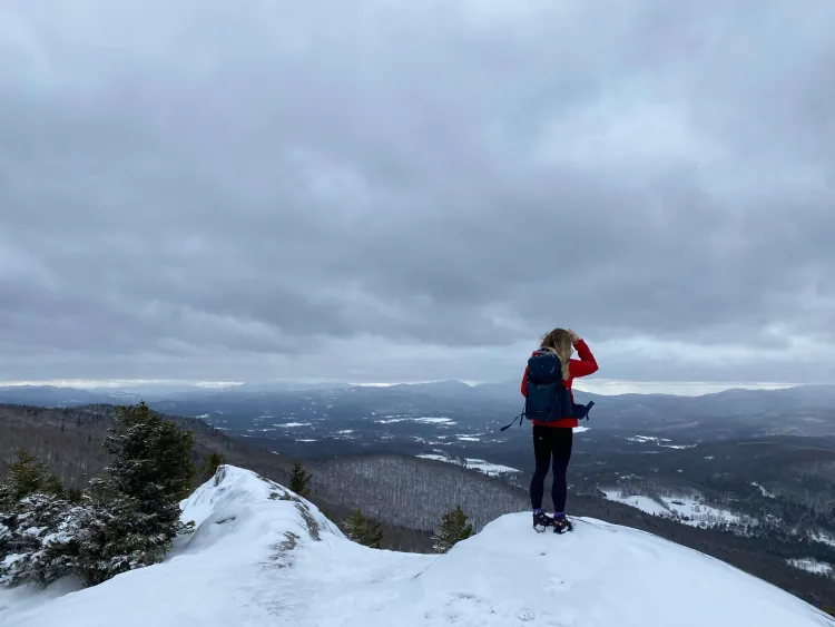 Cat Mawn on a snowy mountain top facing out at the horizon.