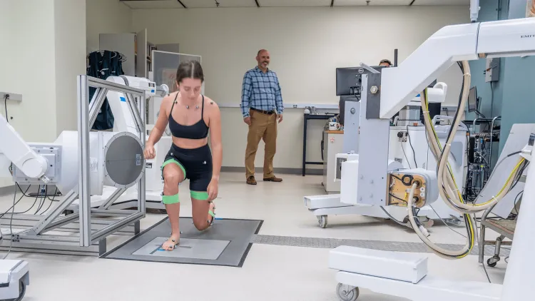 a person kneeling in a lunge while another person looks on