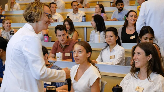 a woman in a white coat greeting members of the Class of 2029