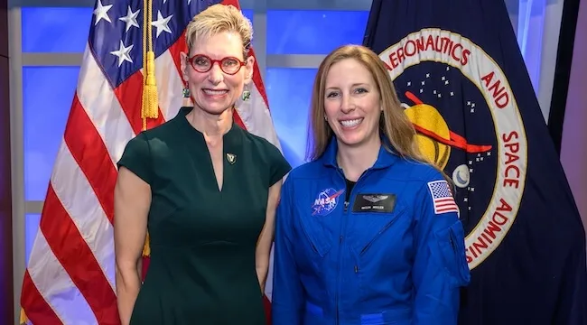 two women pose infornt of the U.S. and NASA flags.