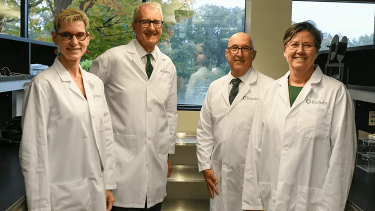 4 people in white coats in a lab space
