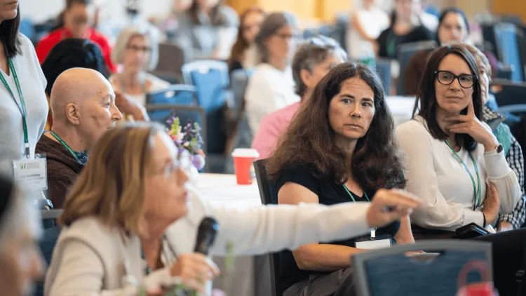 a woman with a microphone in a group of people at a conference