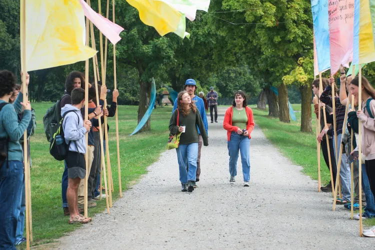 Three UVM students walking along a road lined with colorful banners that people are holding with earth charter principles on them