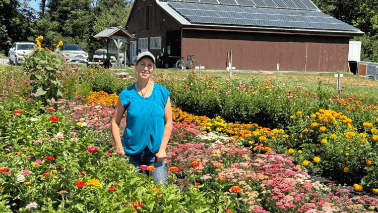 Woman standing on a farm with flowers and a farm stand