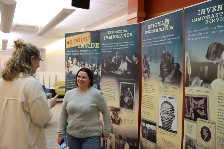 UVM staff discuss the exhibit by the panels in Dana