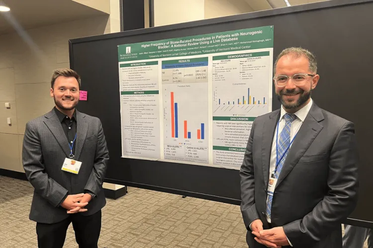 2 people standing by a research poster at a conference