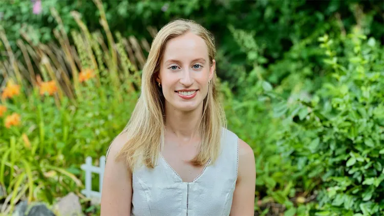 Portrait of a person outdoors with greenery and flowers in the background.
