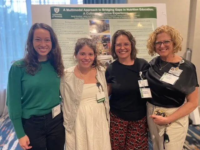 Four women standing in front of an academic poster