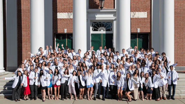 a large group of medical students in white coats posing in front of a building