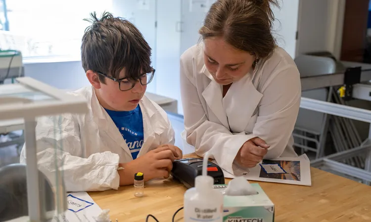a summer camp student works alongside an instructor on a water project