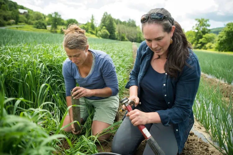 Two women kneel in a field