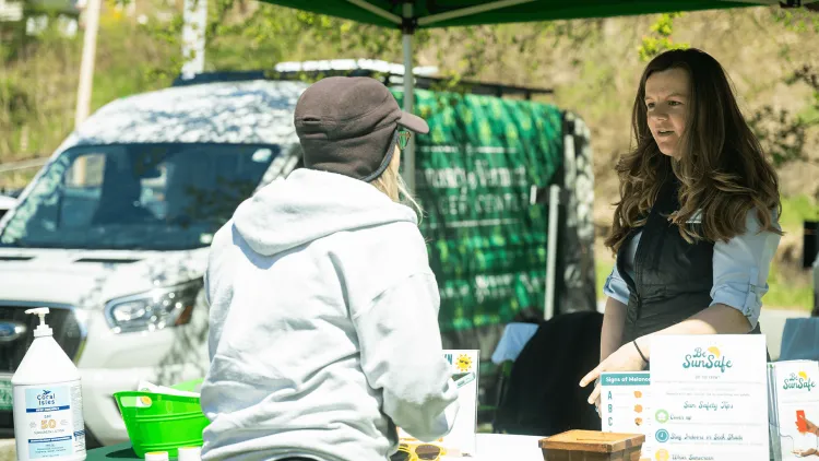 2 people talking near a Cancer Center-branded education and outreach van