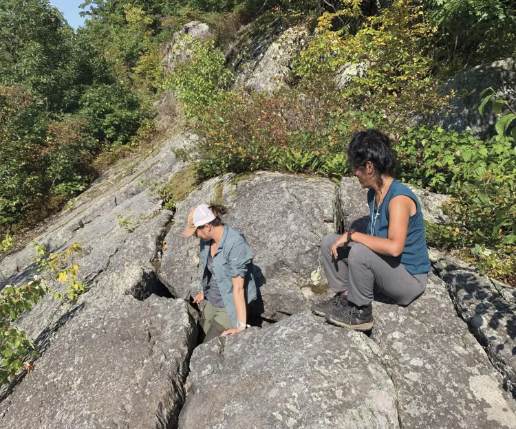 woman emerging from a rock crevice as another woman watches