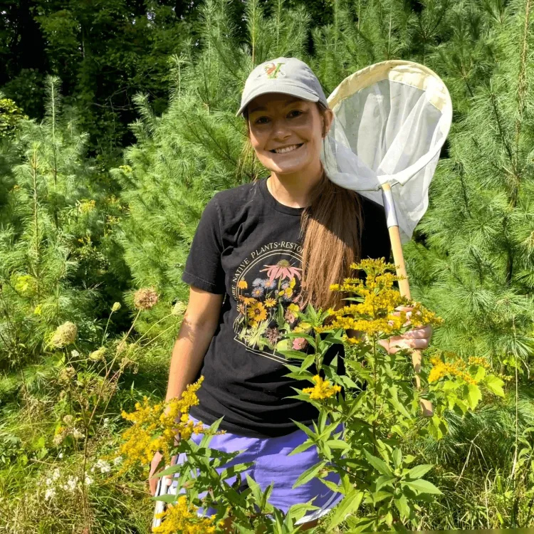 Maddy standing in a field with a bug net