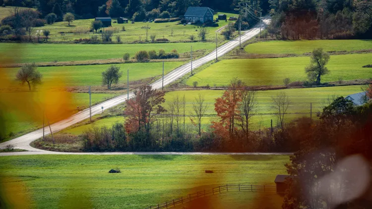 a long, winding road in the country with a house in the distance