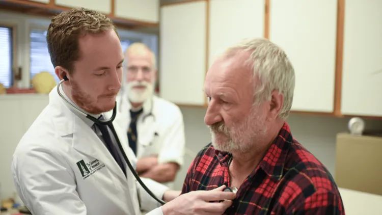 2 doctors with a patient in a flannel shirt