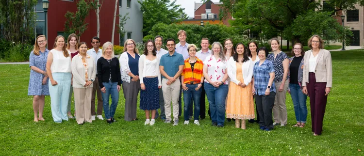 a group of people stand side to side on grass