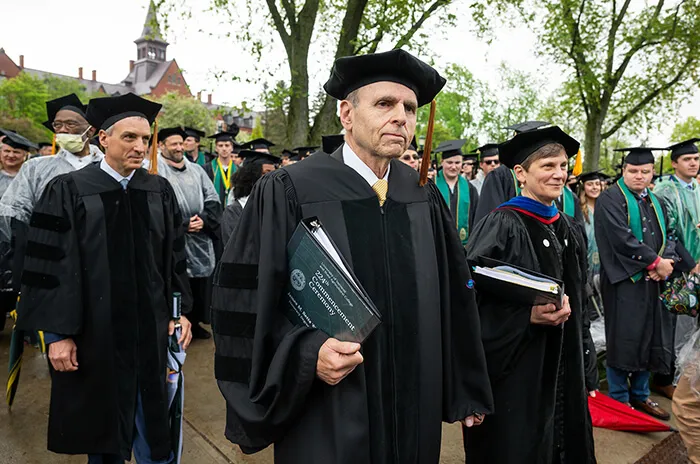 professors in robes walk at a outdoor graduation ceremont