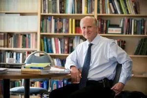 Man sitting at table with library behind