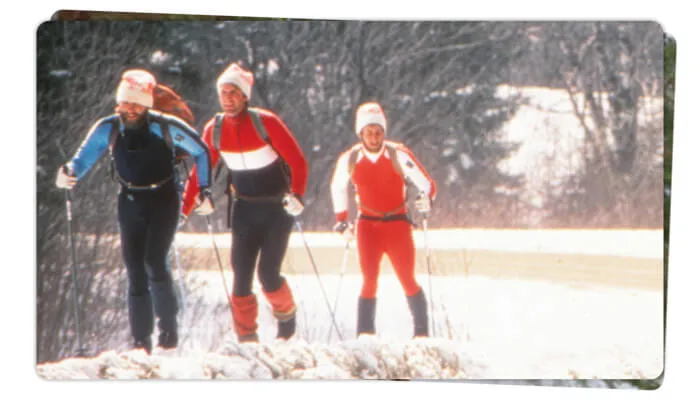 three men wearing winter clothes cross country skiing