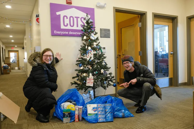 2 people with a Christmas tree and holiday donations