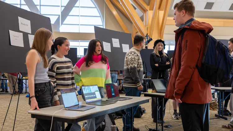 Three students sharing their computer science fair project with a visitor