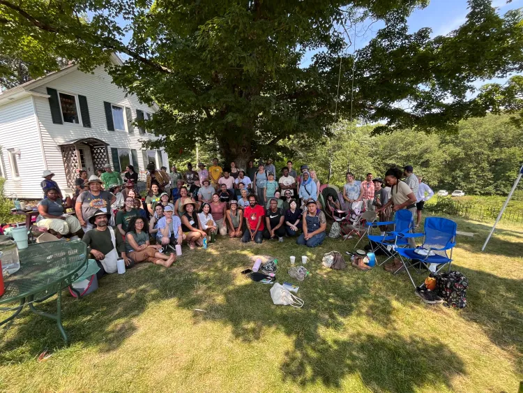Group of people under a tree in front of a house