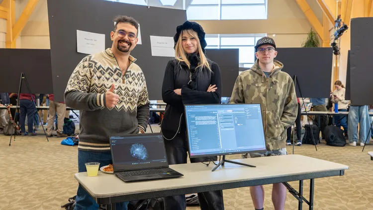Three students pose with their project at a Computer Science Fair