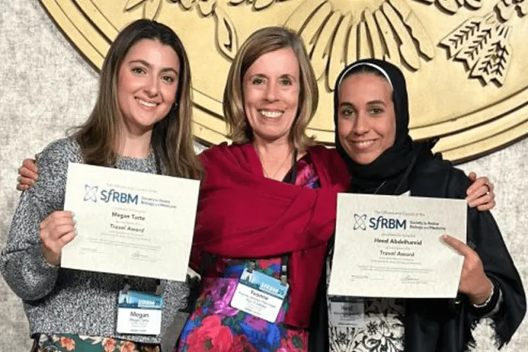 3 people standing holding 2 awards